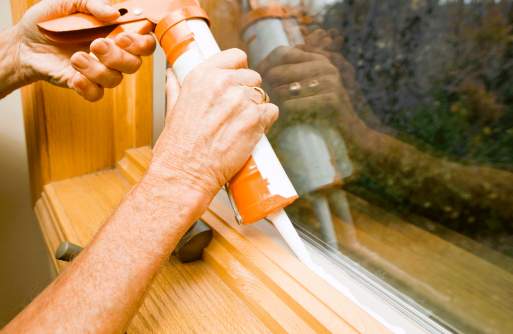 Young man putting sealing foam tape on window indoors