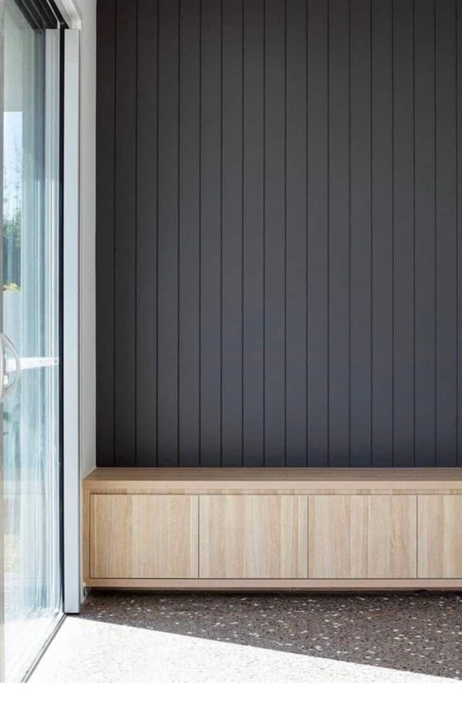 Modern interior wall design with vertical dark paneling and bench