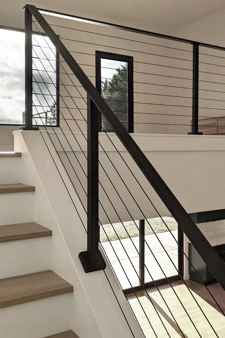 Modern staircase with black metal cable railing and wood steps