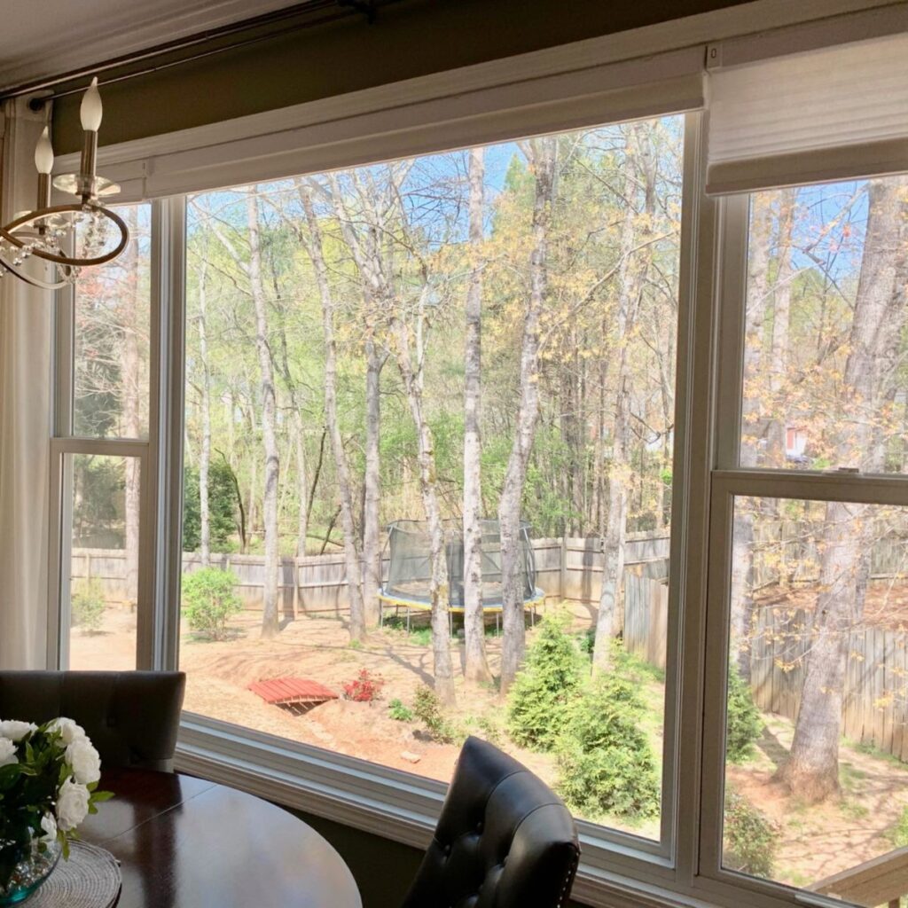 Large picture window with scenic backyard and forest view