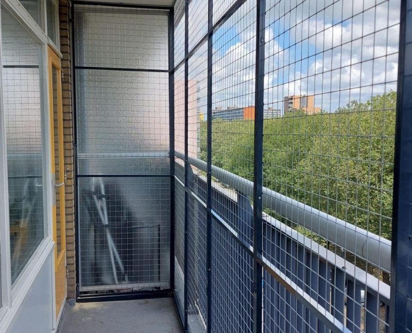 Enclosed balcony with metal safety mesh and glass partition panels