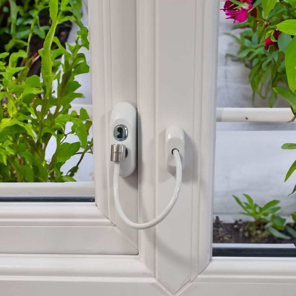 Child safety window lock cable installed on white frame