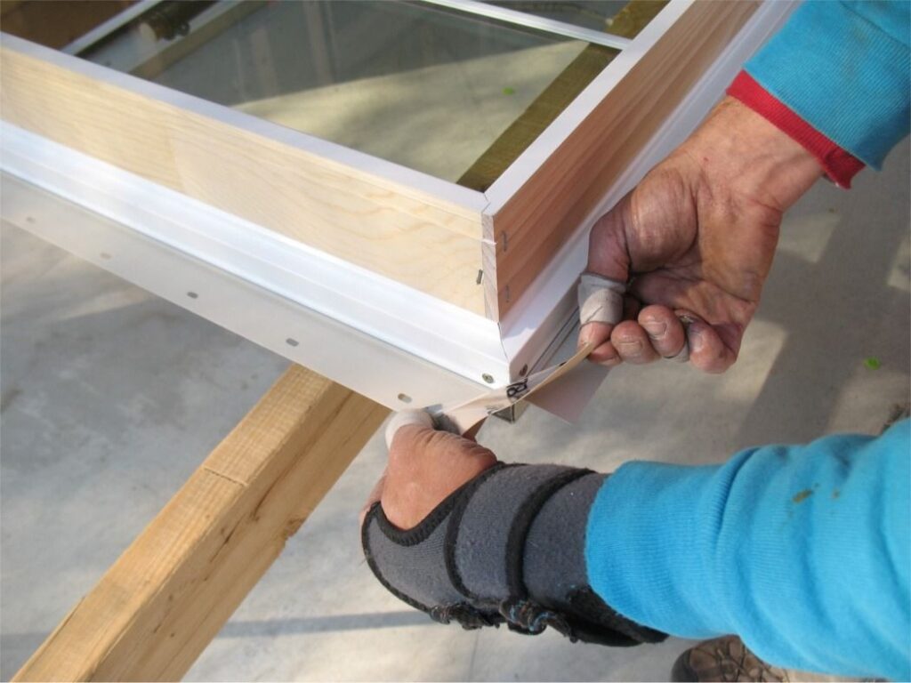 Installer sealing window flange with flashing tape for waterproof fit